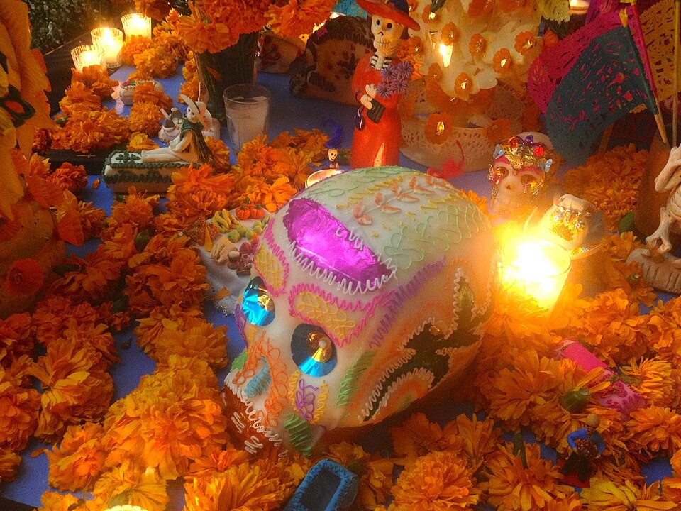 メキシコの死者の日の祭壇。オレンジのマリーゴールドと、砂糖でできたカラフルなガイコツ